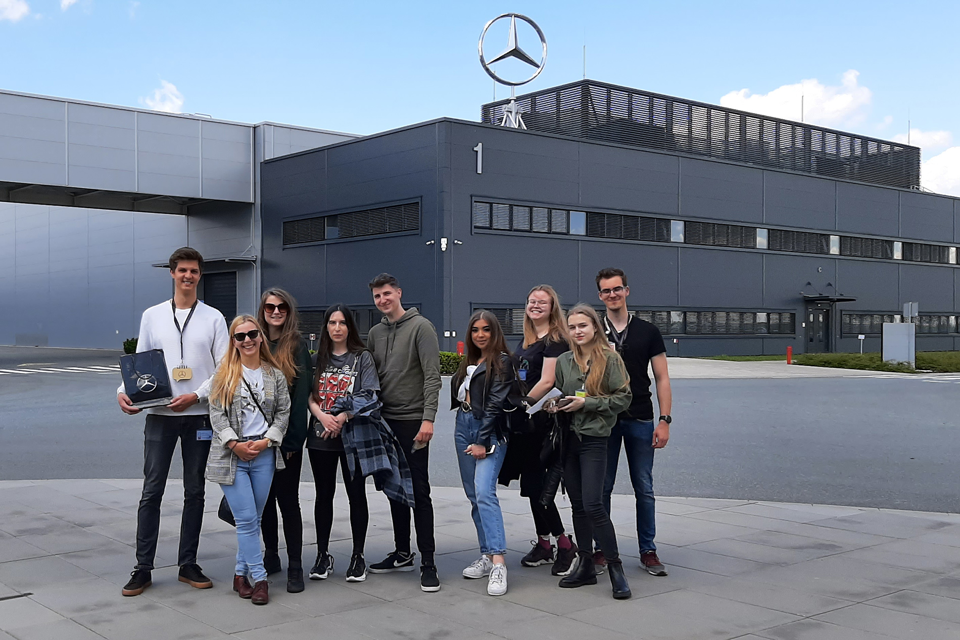 Członkowie Koła Naukowego Logistyki i Transportu PM na tle fabryki Mercedes-Benz