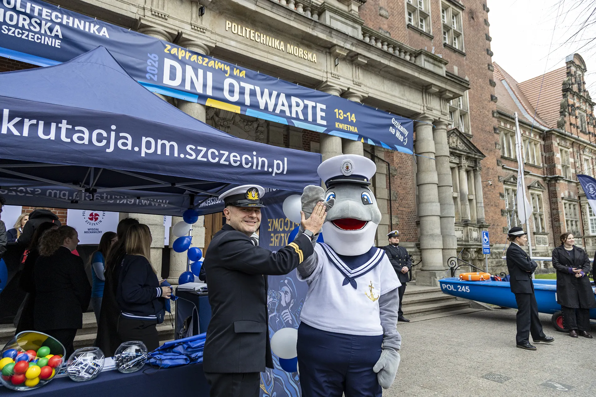 Rafał Zaweracz  Działu Promocji PM i maskotka morświn Michu przed uczelni podczas Dni Otwartych PM