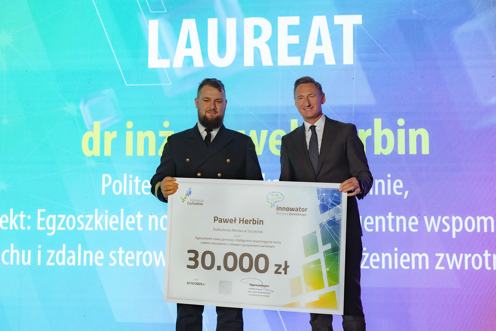 Paweł Herbin  odbiera symboliczny czek z rąk  Marszałka zachodniopomorskiego Olgierda Geblewicza, fot. Urząd Marszałkowski WZ