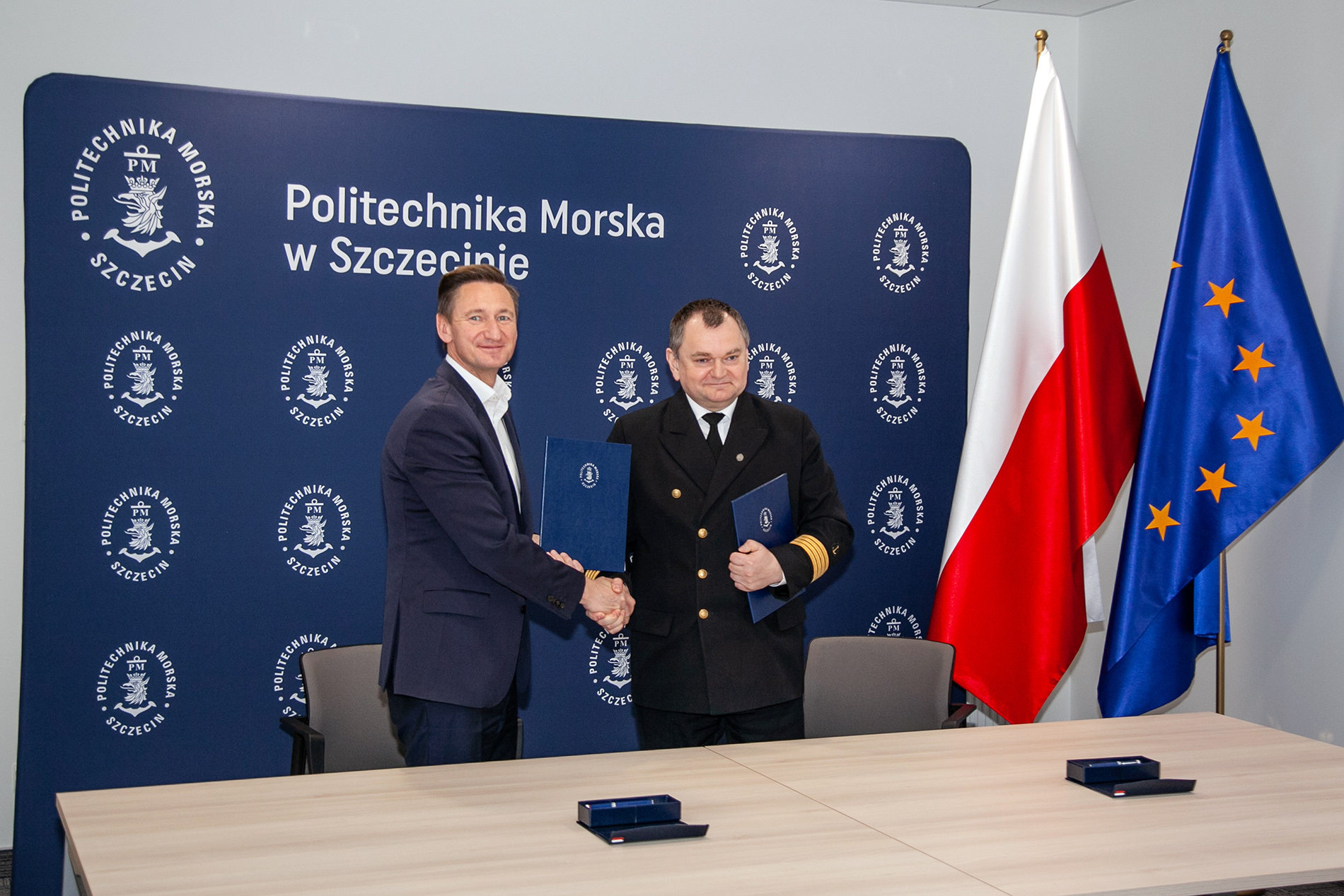 Rektor PM Wojciech Ślączka oraz Marszałek Województwa Zachodniopomorskiego Olgierd Geblewicz na tle ścianki PM, flag Polski i UE podają sobie dłonie po podpisaniu porozumienia, na tle ścianki PM, flag Polski i UE