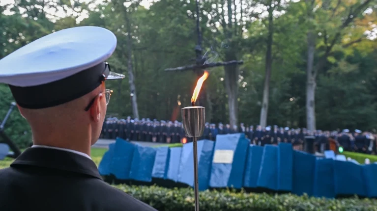 Student PM z pochodnią na tle pomnika "Tym, którzy nie powrócili z morza" na Cmentarzu Centralnym