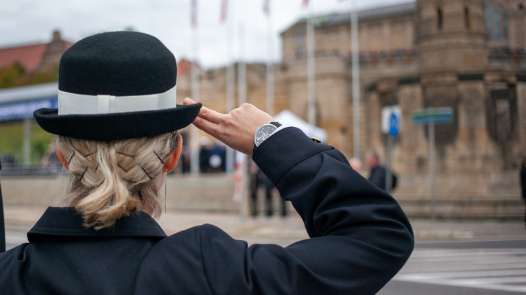 Studenta pierwszego roku PM salutuje podczas uroczystości inauguracji roku akademickiego 2024/25 