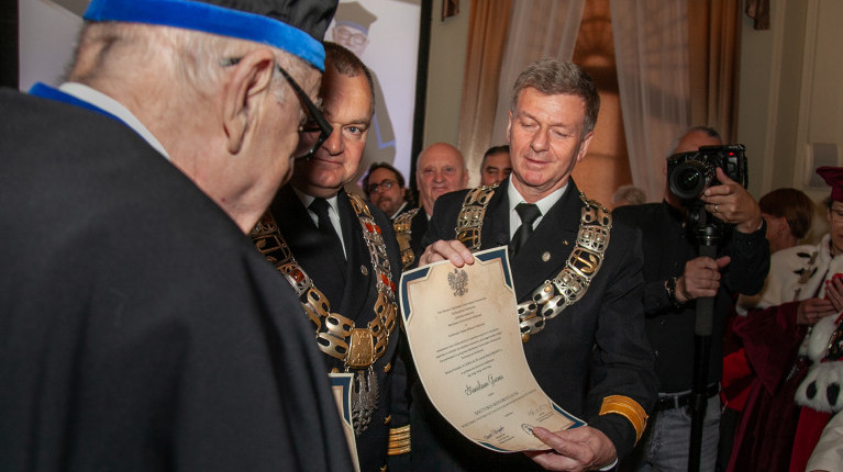Prorektor PM Artur Bejger prezentuje  dyplom DHC prof. Stanisława Gucmy