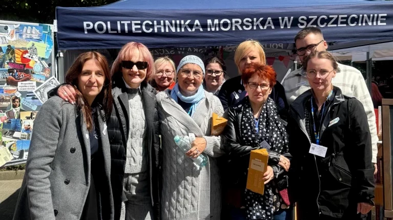 Kadra Biblioteki PM z Martą Barańską przy namiocie z kiermaszem charytatywnym podczas pikniku z okazji Święta Szkoły PM