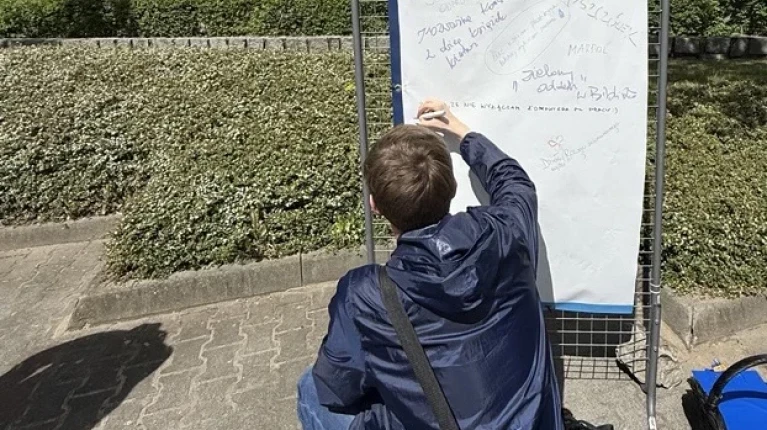 Student PM pisze hasło na banerze "Zostaw swój ślad SDG"