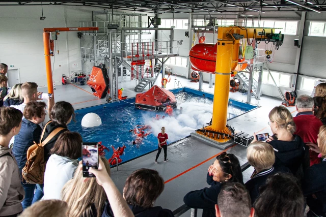 Publiczność spogląda z góry na studentów w basenie podczas ćwiczeń