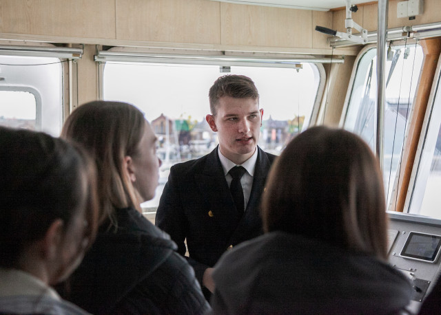 Na mostku nawigacyjnym student opowiada uczniom o statku Nawigator XXI