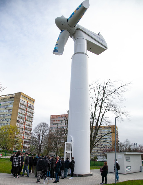 Grupa uczniów przed szkoleniową turbiną wiatrową