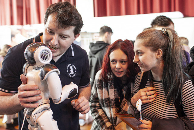 Dr inż. Łukasz Nozdrzykowski  z WIiT demonstruje robota humanoidalnego uczennicom szkół średnich na targach edukacyjnych Edu Day 2023 w Szczecinie