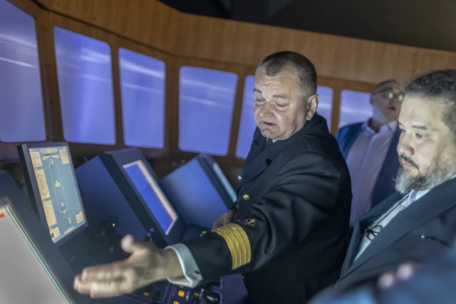 Rektor PM Wojciech Ślączka objaśnia gościom specyfikę symulatora mostka nawigacyjnego w CIRM