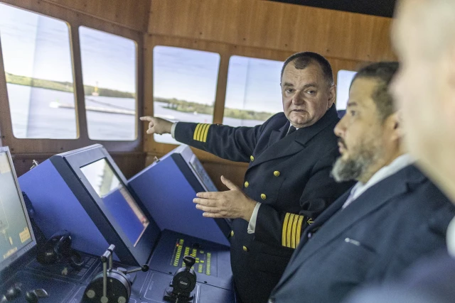 Rektor PM Wojciech Ślączka objaśnia gościom specyfikę symulatora mostka nawigacyjnego w CIRM