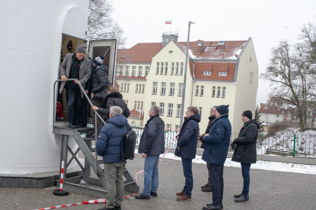 Uczestnicy konferencji zaglądają do wnętrza szkoleniowej turbiny wiatrowej na terenie Wydziału Mechanicznego PM