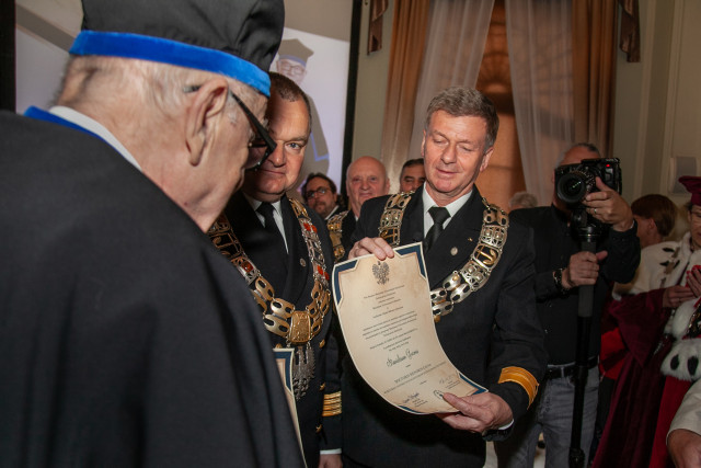 Prorektor PM Artur Bejger prezentuje  dyplom DHC prof. Stanisława Gucmy