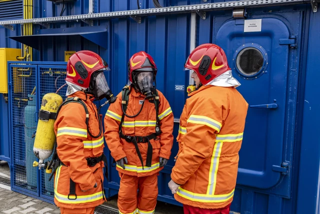 Dwoje studentów i instruktor przed komorą rozgorzeniowo-dymową