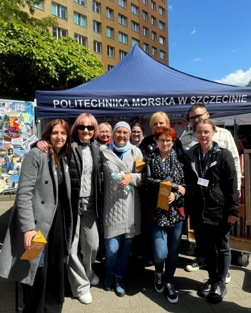 Kadra Biblioteki PM z Martą Barańską przy namiocie z kiermaszem charytatywnym podczas pikniku z okazji Święta Szkoły PM