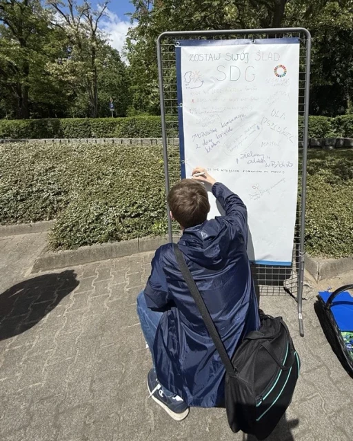 Student pisze hasło na banerze w strefie SDG