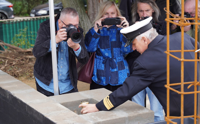 Dean of the Faculty of Mechatronics and Electrical Engineering Maciej Kozak laying the dedicated metal tube with the Foundation Act inside the wall.