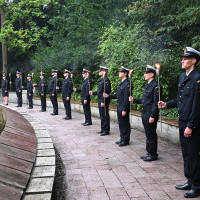 Studenci w mundurach Politechniki Morskiej w Szczecinie z pochodniami podczas uroczystości pod pomnikiem "Tym, którzy nie powrócili z morza" na Cmentarzu Centralnym