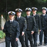 Studenci PM w mundurach z pochodniami podczas uroczystości pod pomnikiem "Tym, którzy nie powrócili z morza" na Cmentarzu Centralnym