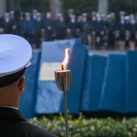 Student PM w mundurze z pochodnią podczas uroczystości pod pomnikiem "Tym, którzy nie powrócili z morza" na Cmentarzu Centralnym