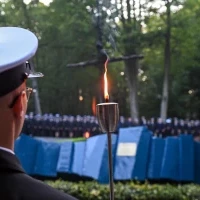 Student PM w mundurze z pochodnią podczas uroczystości pod pomnikiem "Tym, którzy nie powrócili z morza" na Cmentarzu Centralnym