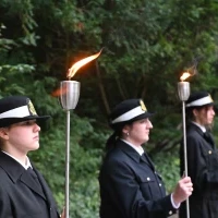Studenci PM w mundurach z pochodniami podczas uroczystości pod pomnikiem "Tym, którzy nie powrócili z morza" na Cmentarzu Centralnym