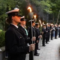 Studenci PM w mundurach z pochodniami podczas uroczystości pod pomnikiem "Tym, którzy nie powrócili z morza" na Cmentarzu Centralnym