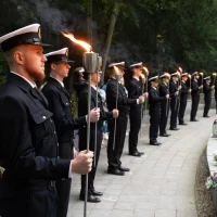 Studenci PM w mundurach z pochodniami podczas uroczystości pod pomnikiem "Tym, którzy nie powrócili z morza" na Cmentarzu Centralnym