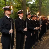 Studenci PM w mundurach z pochodniami podczas uroczystości pod pomnikiem "Tym, którzy nie powrócili z morza" na Cmentarzu Centralnym