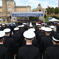 Studenci w mundurach stoją przed trybuną honorową z gośćmi przybyłymi na inaugurację roku akademickiego Politechniki Morskiej w Szczecinie