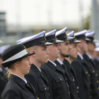 Studentka w mundurze na tle pododdziału mundurowych studentów I roku Politechniki Morskiej podczas uroczystości inauguracji nowego roku akademickiego 2022/23 na PM