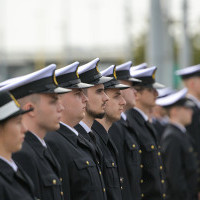 Studentka w mundurze na tle pododdziału mundurowych studentów I roku Politechniki Morskiej podczas uroczystości inauguracji nowego roku akademickiego 2022/23 na PM