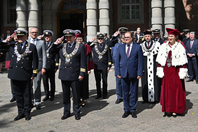 Przedstawiciele władz zachodniopomorskich uczelni i zaproszeni goście oglądają przed budynkiem AMS musztrę paradną z okazji 75-lecia szkolnictwa morskiego na Pomorzu Zachodnim