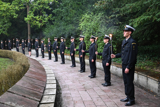 Studenci w mundurach Politechniki Morskiej w Szczecinie z pochodniami podczas uroczystości pod pomnikiem "Tym, którzy nie powrócili z morza" na Cmentarzu Centralnym