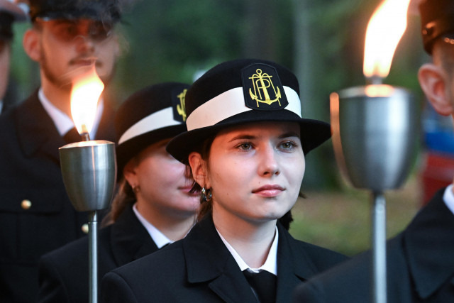 Studenci w mundurach Politechniki Morskiej w Szczecinie z pochodniami podczas uroczystości pod pomnikiem "Tym, którzy nie powrócili z morza" na Cmentarzu Centralnym