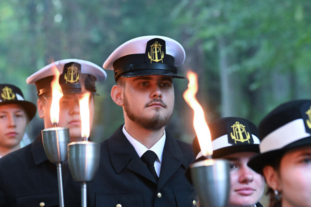 Studenci w mundurach Politechniki Morskiej w Szczecinie z pochodniami podczas uroczystości pod pomnikiem "Tym, którzy nie powrócili z morza" na Cmentarzu Centralnym