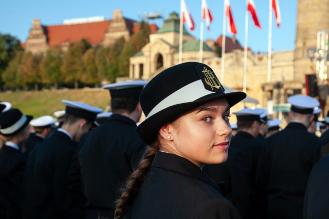 Studentka I roku na inauguracji roku akademickiego PM na tle budynku uczelni