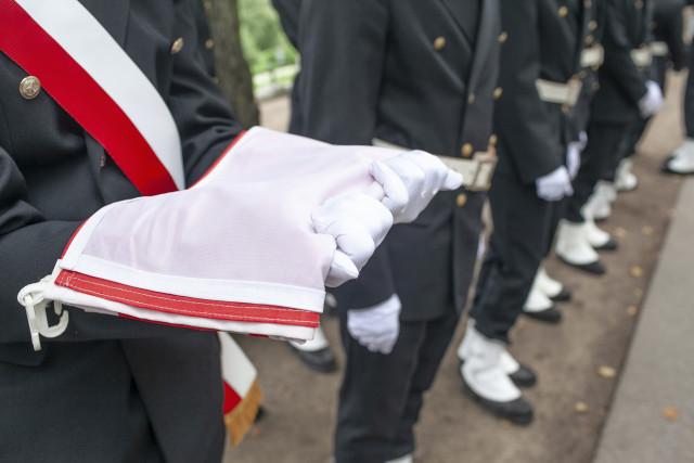 Członek Pocztu sztandarowego Politechniki Morskiej w Szczecinie trzyma złożoną flagę państwową