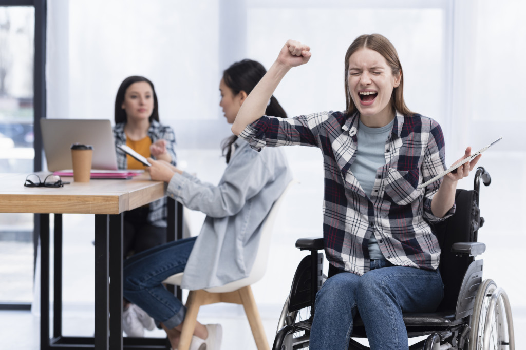 zdjęcie zadowolonej studentki poruszającej się na wózku dla osób z niepełnosprawnością