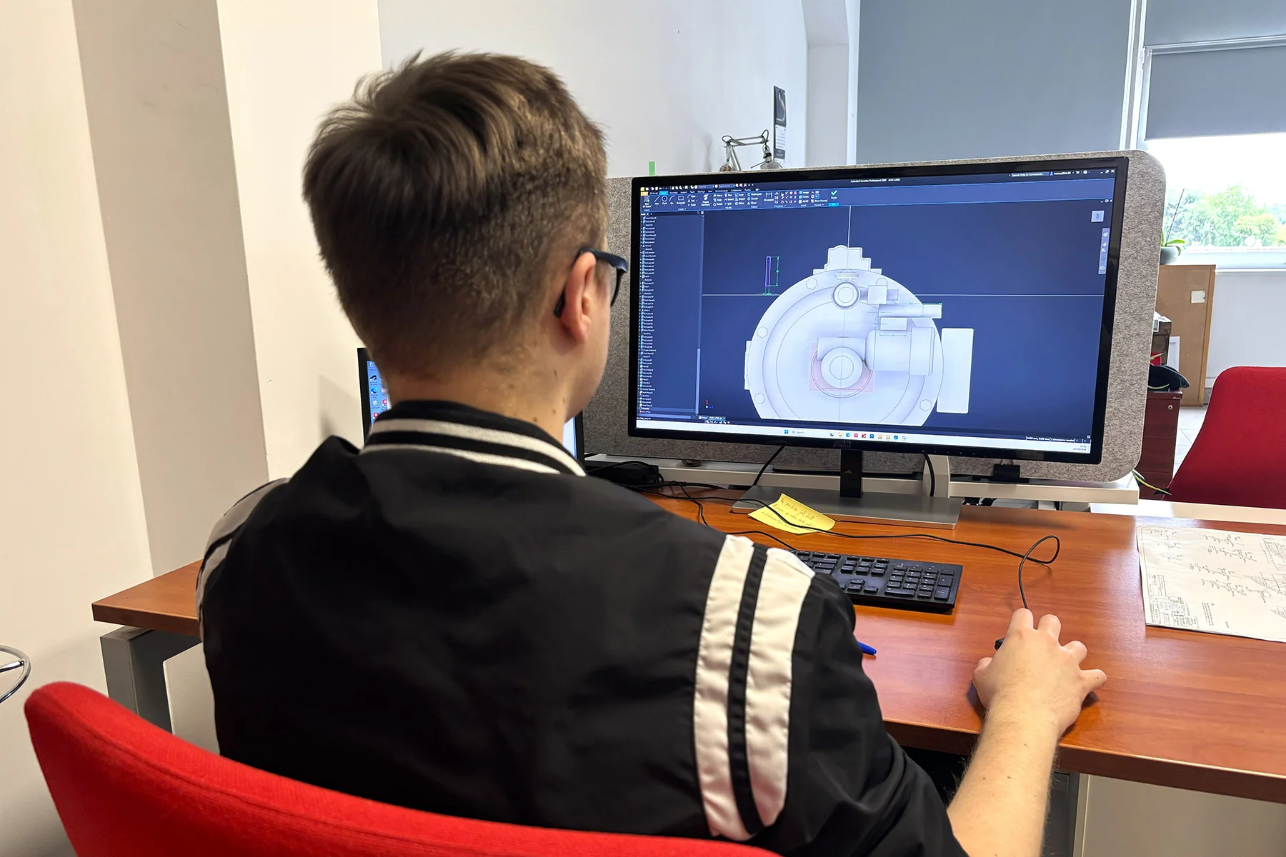 Student inzynierii modelowania przestzrennego przy monitorze z modelami 3D