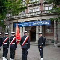 Studenci z Kompanii Honorowej i Pocztu Sztandarowego PM wraz z dowódcą stoją przed budynkiem PM na Wałach Chrobrego