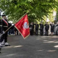 Kompania Honorowa PM z pocztem sztandarowym i dowódcą oraz pracownicy PM podczas uroczystości wciągnięcia bandery przy budynku uczelni z okazji Święta Szkoły 