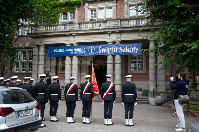 Studenci z Kompanii Honorowej i Pocztu Sztandarowego PM wraz z dowódcą stoją przed budynkiem PM na Wałach Chrobrego