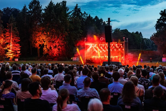 Widok widowni i rozświetlonej sceny z artystami po zmierzchu