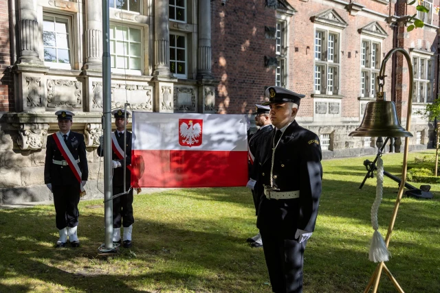 Studenci z Kompanii Honorowej PM wciągają na maszt banderę przed budynkien uczelni z okazji Święta Szkoły