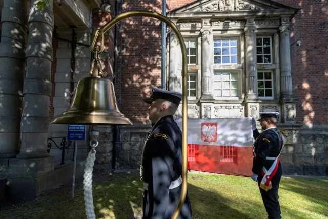 Studenci z Kompanii Honorowej PM wciągają na maszt banderę przed budynkien uczelni z okazji Święta Szkoły