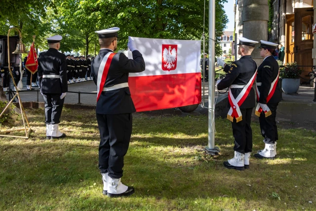 Studenci z Kompanii Honorowej PM prezentują banderę przed budynkiem uczelni w dniu Święta Szkoły