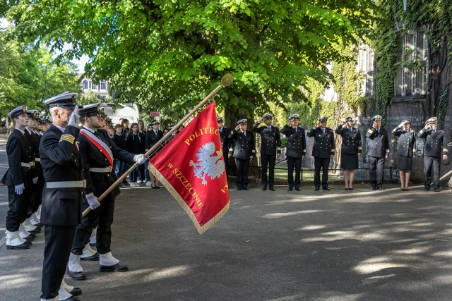 Kompania Honorowa PM z pocztem sztandarowym i dowódcą oraz pracownicy PM podczas uroczystości  wciągnięcia bandery przy budynku uczelni z okazji Święta Szkoły 