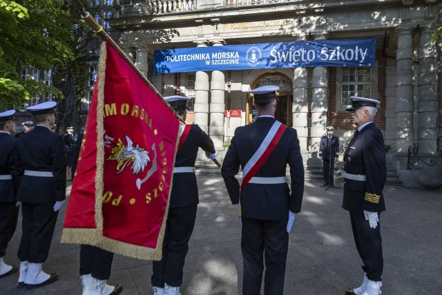 Kompania Honorowa PM z pocztem sztandarowym i dowódcą oraz pracownicy PM podczas uroczystości  wciągnięcia bandery przy budynku uczelni z okazji Święta Szkoły 