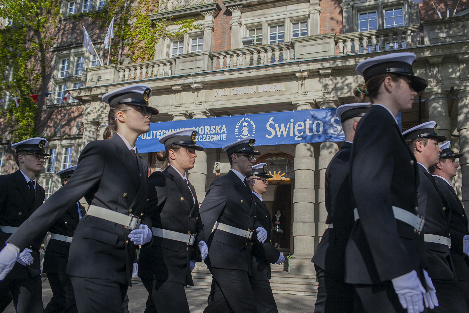 Kompania Honorowa PM maszeruje przed głównym wejściem do uczelni